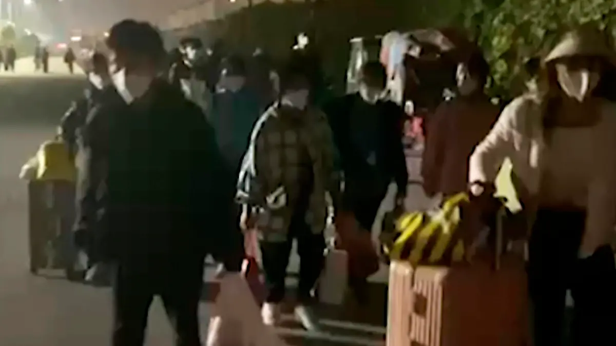 SCREENSHOT - 30.10.2022, China, Zhengzhou: HANDOUT - Dieses Videostandbild zeigt Menschen mit Koffern und Taschen, die nach einem Corona-Lockdown das Werksgelände des Apple-Zulieferers Foxconn in Zhengzhou verlassen. Foto: Hangpai Xingyang/Hangpai Xingyang/dpa - ACHTUNG: Nur zur redaktionellen Verwendung bis zum 13.11.2022 im Zusammenhang mit der aktuellen Berichterstattung und nur mit vollständiger Nennung des vorstehenden Credits +++ dpa-Bildfunk +++