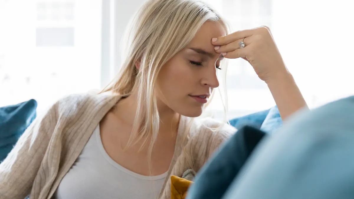 Woman with headache siting on sofa, Frau mit dem Kopfweh-Stationieren auf der Couch