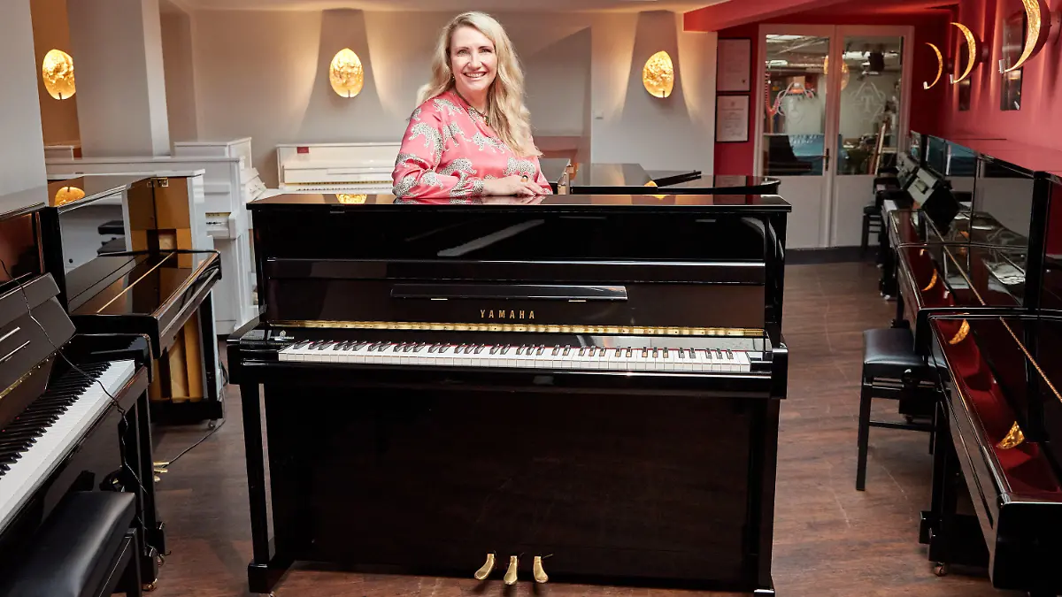 25.08.2022, Hamburg: Yvonne Trübger, Inhaberin, steht hinter einem von 15 Klavieren, das anlässlich des 150. Jubiläums des Pianohauses Trübger gespendet werden soll. Das Pianohaus gehört zu den letzten Pianohäusern, die nicht nur eine Marke vertreten. (zu dpa "Pianohaus Trübger verschenkt zum 150-jährigen Bestehen 15 Klaviere") Foto: Georg Wendt/dpa +++ dpa-Bildfunk +++