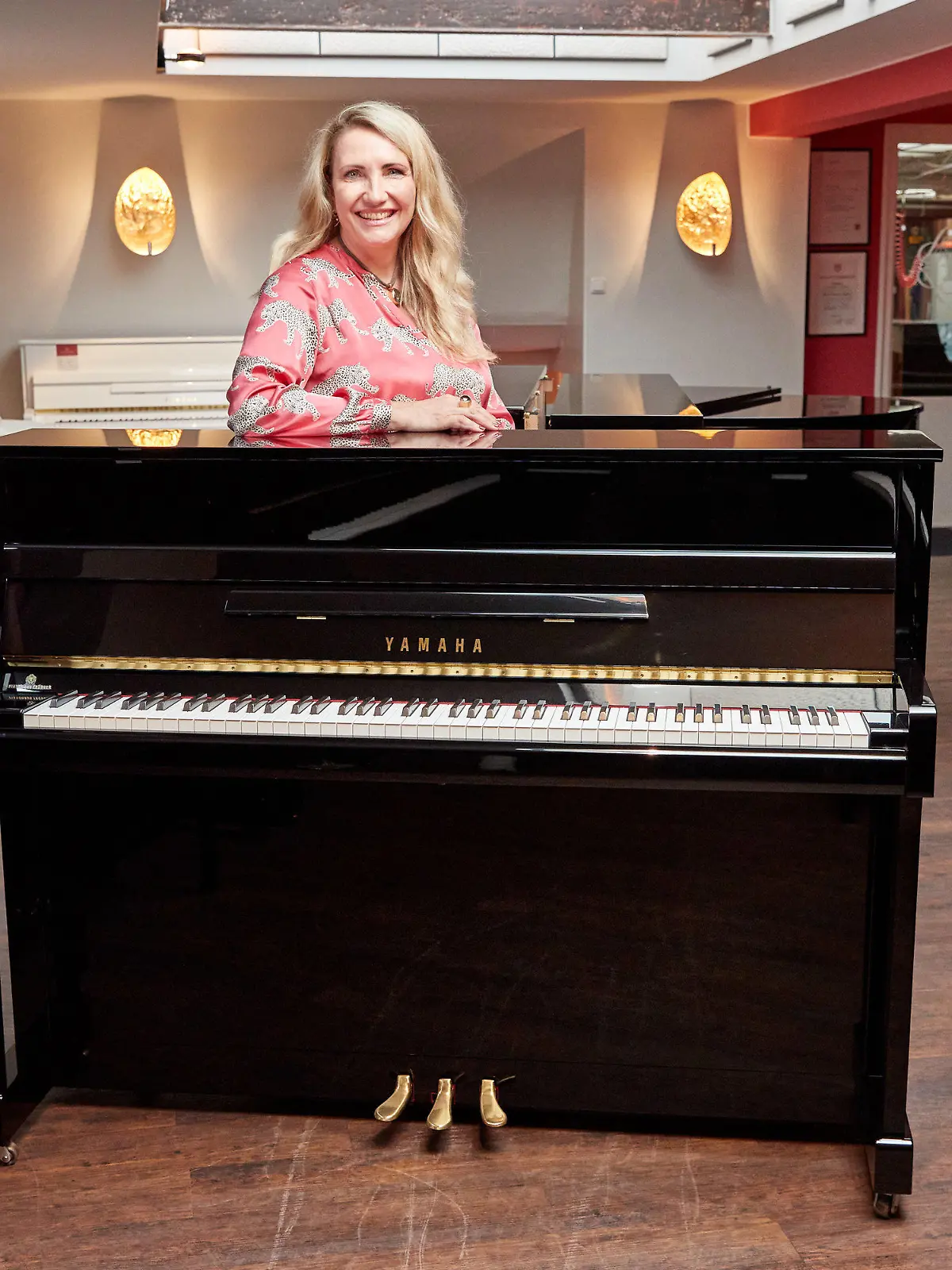 25.08.2022, Hamburg: Yvonne Trübger, Inhaberin, steht hinter einem von 15 Klavieren, das anlässlich des 150. Jubiläums des Pianohauses Trübger gespendet werden soll. Das Pianohaus gehört zu den letzten Pianohäusern, die nicht nur eine Marke vertreten. (zu dpa "Pianohaus Trübger verschenkt zum 150-jährigen Bestehen 15 Klaviere") Foto: Georg Wendt/dpa +++ dpa-Bildfunk +++
