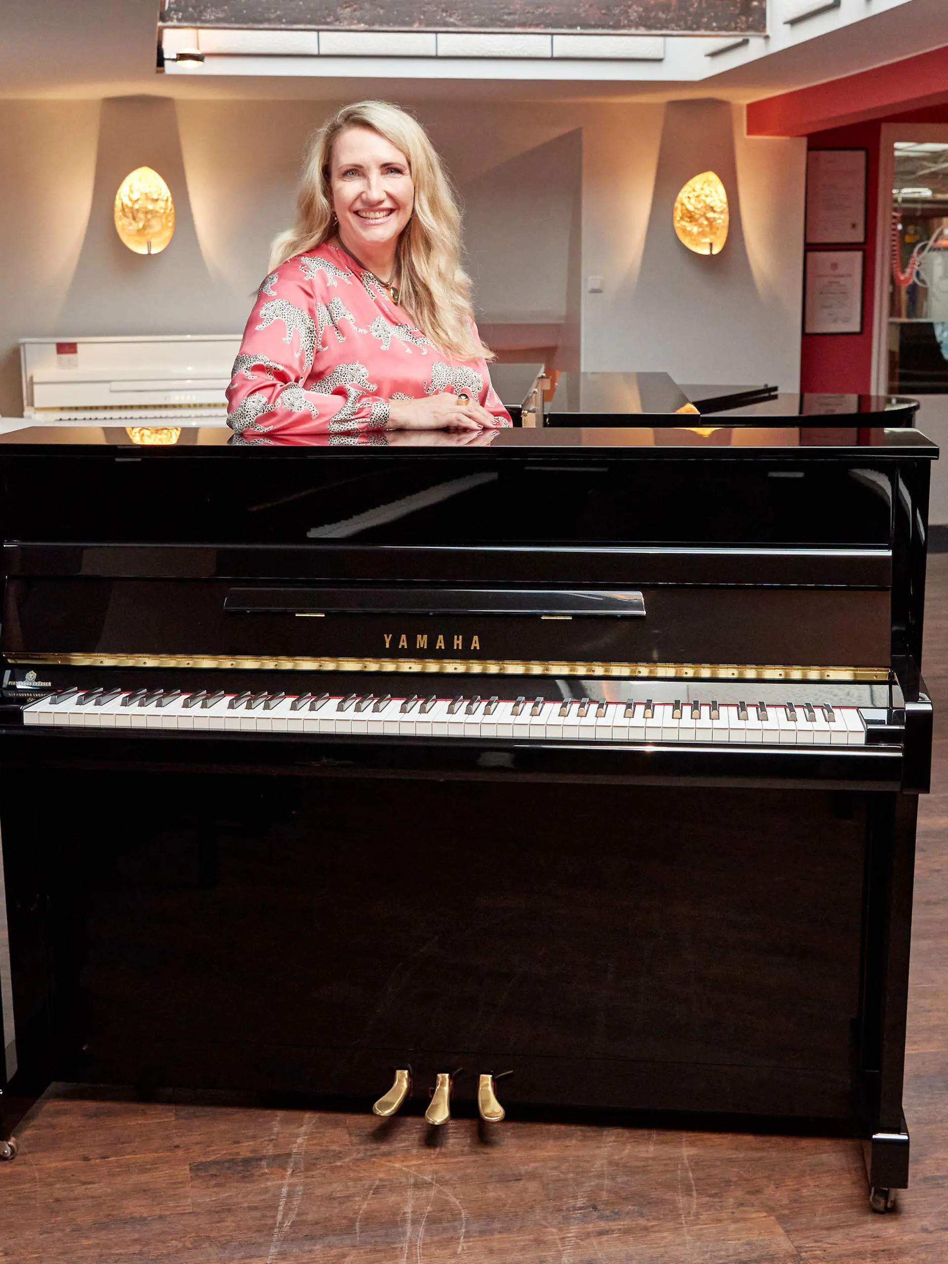 25.08.2022, Hamburg: Yvonne Trübger, Inhaberin, steht hinter einem von 15 Klavieren, das anlässlich des 150. Jubiläums des Pianohauses Trübger gespendet werden soll. Das Pianohaus gehört zu den letzten Pianohäusern, die nicht nur eine Marke vertreten. (zu dpa "Pianohaus Trübger verschenkt zum 150-jährigen Bestehen 15 Klaviere") Foto: Georg Wendt/dpa +++ dpa-Bildfunk +++