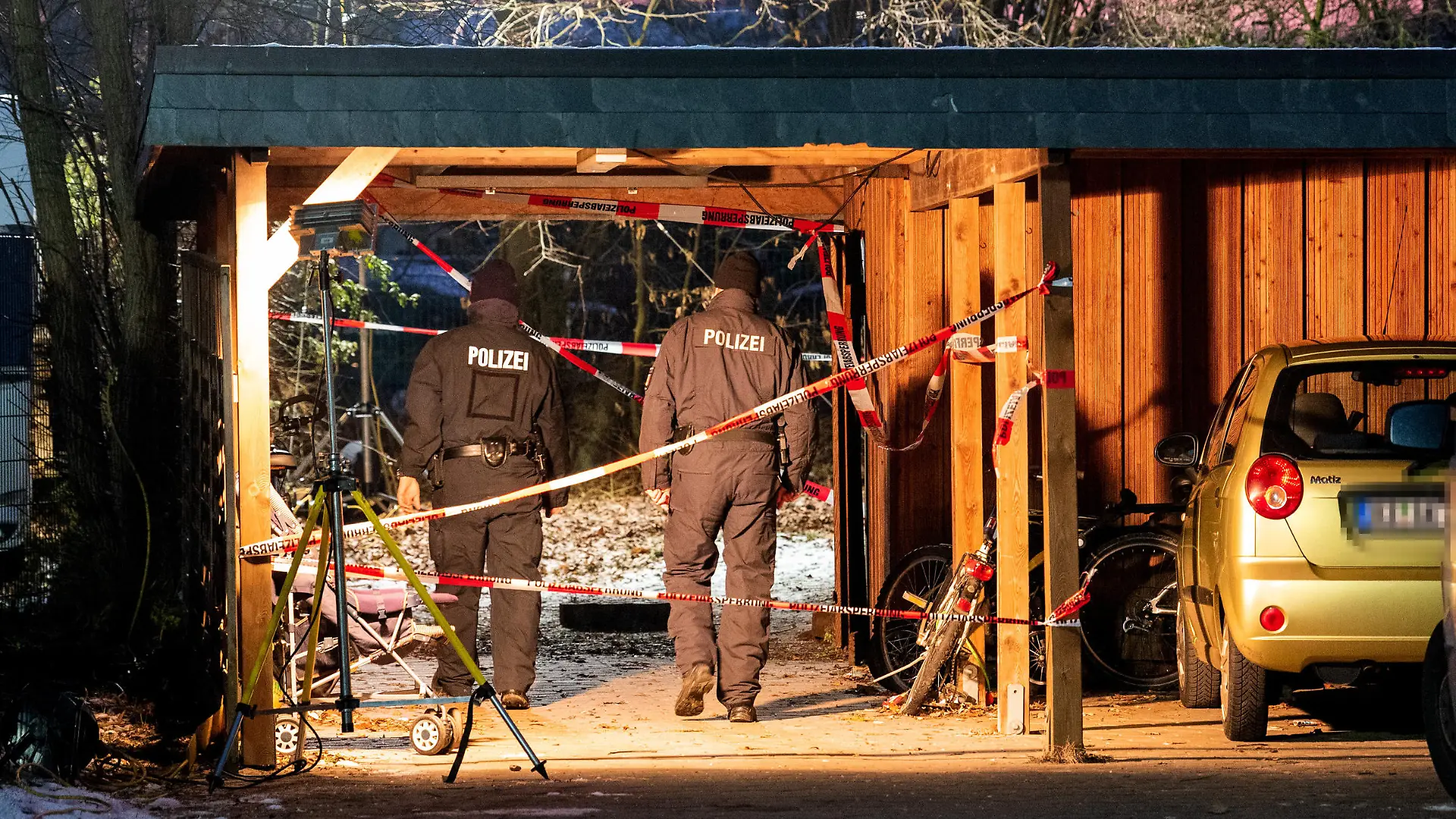 12.12.2022, Schleswig-Holstein, Alt Mölln: Ermittler der Polizei stehen hinter einem Mehrfamilienhaus am Zugang zu einem Garten. Dort wurde am Mittag in einem Erdloch eine vergrabene Leiche gefunden. Foto: Daniel Bockwoldt/dpa +++ dpa-Bildfunk +++