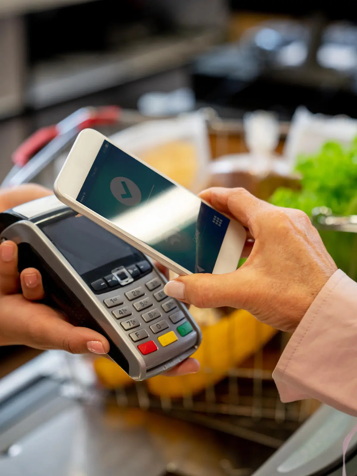 Unrecognizable female customer paying for groceries with smartphone **DESIGN ON SCREEN WAS MADE FROM SCRATCH BY US**