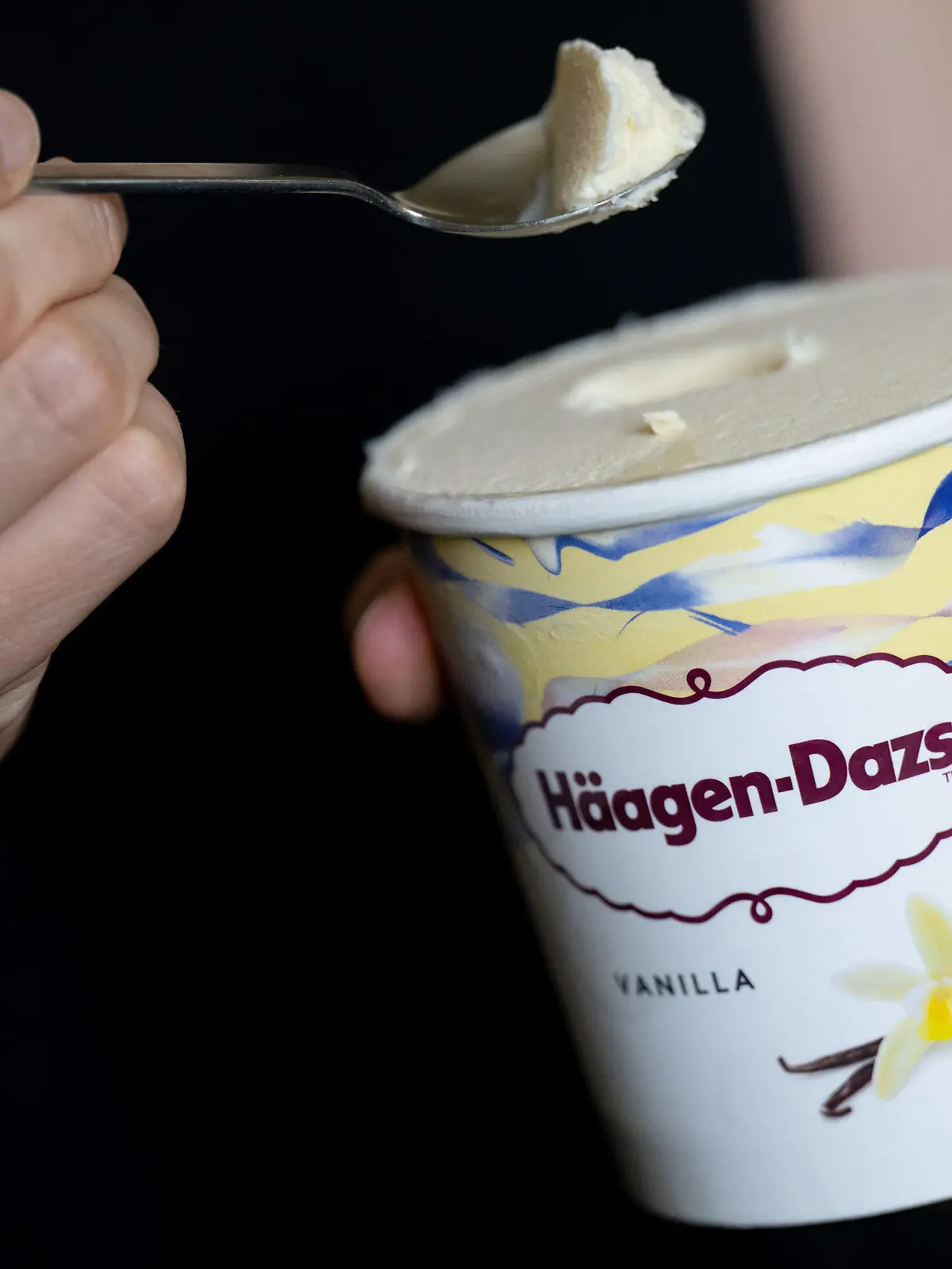 14.07.2022, Bayern, München: Eine Frau hält einen Löffel und einen Becher Eis "Vanilla" von Häagen-Dazs in den Händen. Der Hersteller General Mills ruft Produkte von Häagen-Dazs mit der Geschmacksrichtung «Vanilla» zurück. Es könne nicht ausgeschlossen werden, dass sich in den Produkten Rückstände von Ethylenoxid befinden. Es gehe um die Größen 460 ml, 95 ml und die Classic Collection 4x95 ml mit dem Mindesthaltbarkeitsdatum 21. Mai 2023. Foto: Sven Hoppe/dpa - ACHTUNG: Nur zur redaktionellen Verwendung und nur mit vollständiger Nennung des vorstehenden Credits +++ dpa-Bildfunk +++