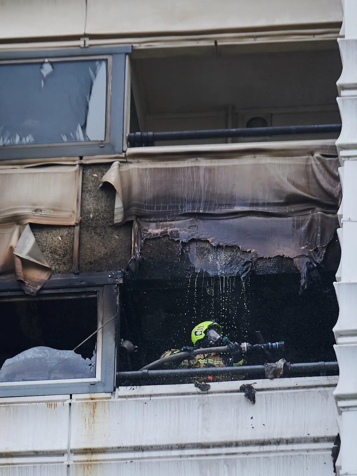 dpatopbilder - 28.07.2023, Berlin: Ein Feuerwehrmann löscht einen Brand in einem Hochhaus. Wegen eines Brandes im zwölften Stock eines Hochhauses in Berlin sind zwei Menschen aus dem Gebäude gesprungen und ums Leben gekommen. Sie starben trotz Reanimation noch an der Unfallstelle, wie ein Feuerwehrsprecher sagte. Das Feuer sei am Freitag im zwölften Stock eines Hochhauses in Berlin-Kreuzberg ausgebrochen. Foto: Annette Riedl/dpa +++ dpa-Bildfunk +++