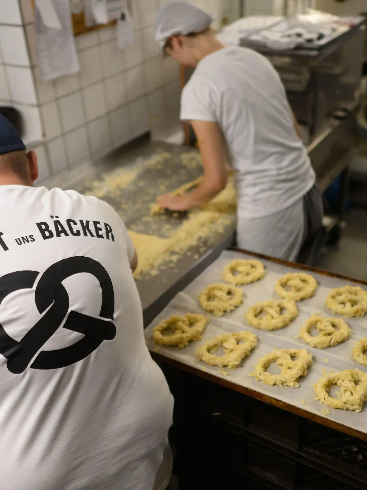 08.09.2022, Niedersachsen, Hannover: Ein Bäcker und eine Auszubildende stehen am frühen Morgen mit einem T-Shirt ·Rettet uns Bäcker· in der Backstube der Bäckerei Fahrenhorst. Die norddeutschen Innungsbäckereien machen am 08. September mit der Aktion ·Uns geht das Licht aus · Heute das Licht und morgen der Ofen?· auf gestiegene Energiekosten aufmerksam, die viele Betriebe in ihrer Existenz bedrohen. Foto: Julian Stratenschulte/dpa +++ dpa-Bildfunk +++