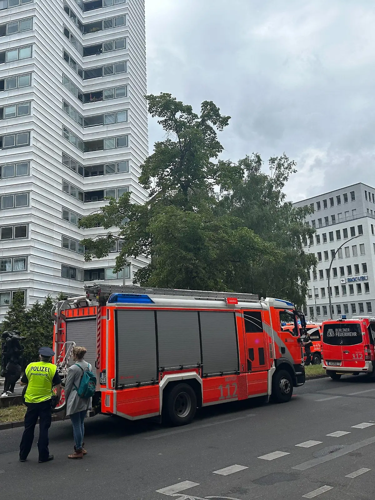 28.07.2023, Berlin: Einsatzkräfte der einem Hochhaus stehen vor einem Hochhaus auf der Straße. Zwei Menschen sind wegen eines Brandes in einem Hochhaus aus dem Gebäude gesprungen und gestorben. Das Feuer sei am Freitag im zehnten Stock eines zwölfgeschossigen Hochhauses ausgebrochen. Foto: Annette Riedl/dpa +++ dpa-Bildfunk +++