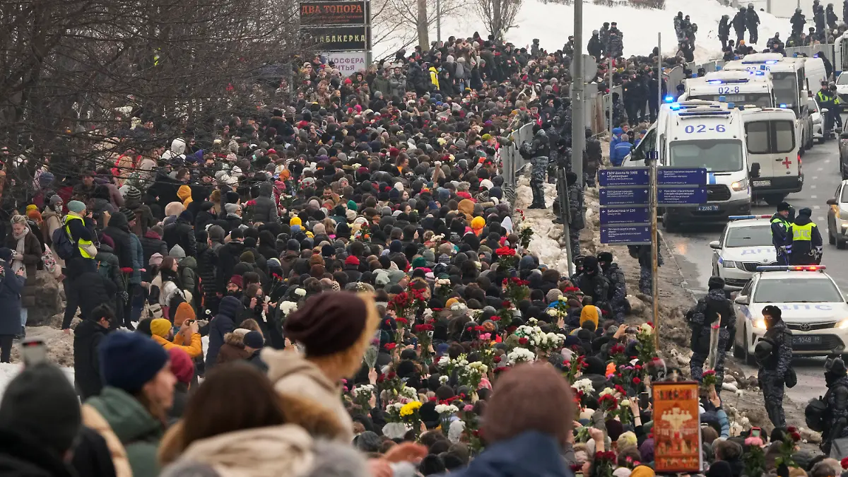 01.03.2024, Russland, Moskau: Polizisten (r) beobachten, wie Menschen zur Beerdigungszeremonie des russischen Oppositionellen Nawalny zum Friedhof Borisowskoje gehen. Unter starker Polizeipräsenz nahmen am Freitag Tausende von Menschen bei der Beerdigung von Alexej Nawalny in Moskau Abschied, der vor zwei Wochen unter noch ungeklärten Umständen in einer arktischen Strafkolonie gestorben war. Foto: Uncredited/AP/dpa +++ dpa-Bildfunk +++