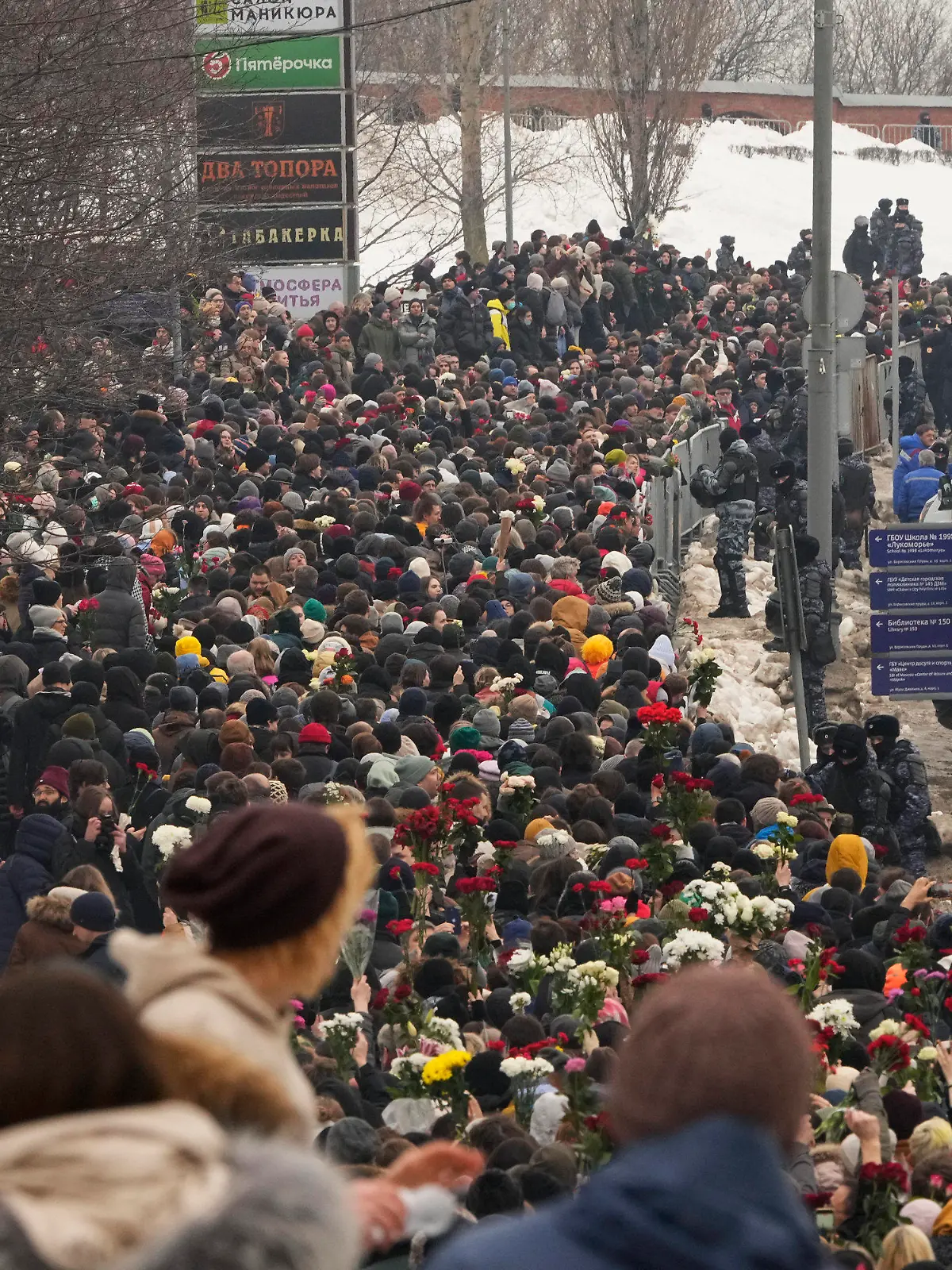 01.03.2024, Russland, Moskau: Polizisten (r) beobachten, wie Menschen zur Beerdigungszeremonie des russischen Oppositionellen Nawalny zum Friedhof Borisowskoje gehen. Unter starker Polizeipräsenz nahmen am Freitag Tausende von Menschen bei der Beerdigung von Alexej Nawalny in Moskau Abschied, der vor zwei Wochen unter noch ungeklärten Umständen in einer arktischen Strafkolonie gestorben war. Foto: Uncredited/AP/dpa +++ dpa-Bildfunk +++