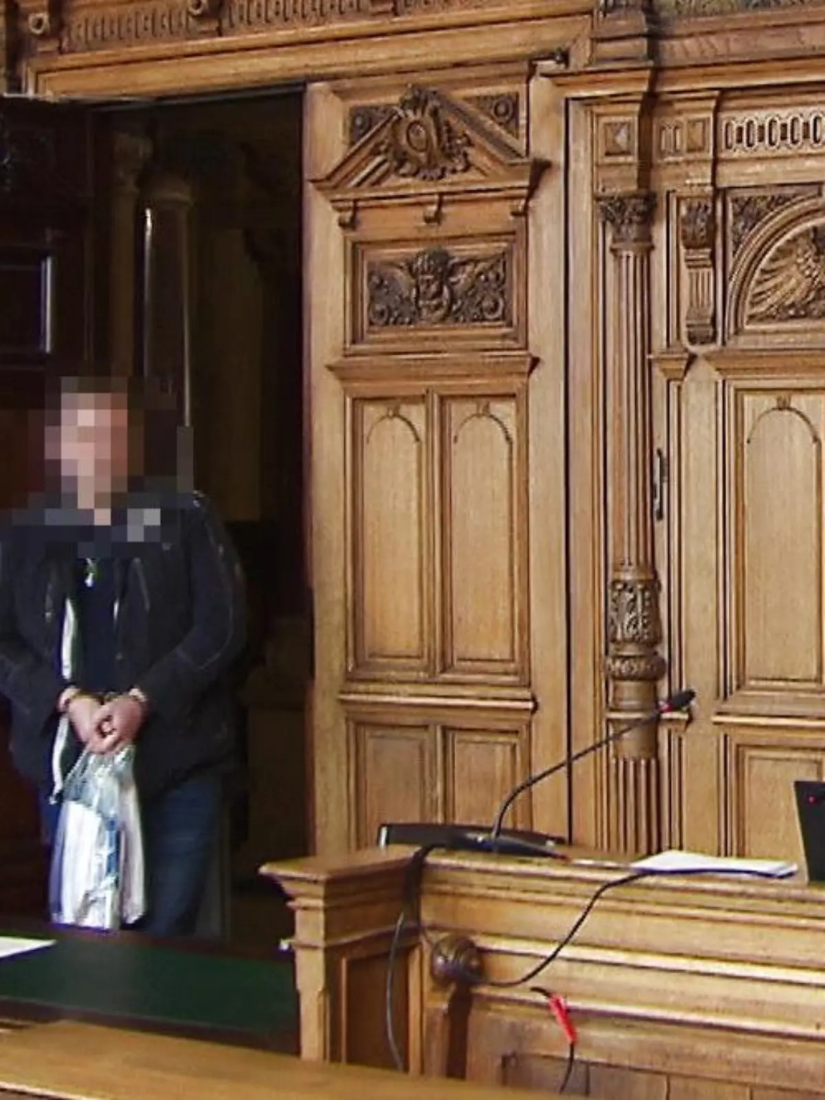 Der Angeklagte Walter B. betritt den Gerichtssaal mit einer Tasche voller Unterlagen.