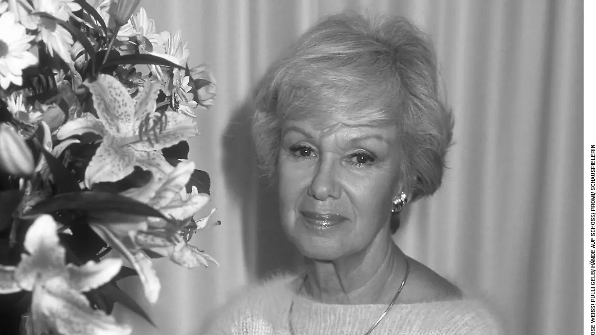 MARIA SEBALDT / AUFNAHMEDATUM UNBEKANNT/ POSIEREN/ HALBFIGUR/ SITZEN/ VOR VORHANG/ NEBEN BLUMEN/ HOSE WEISS/ PULLI GELB/ HÄNDE AUF SCHOSS/ PROMI/ SCHAUSPIELERIN