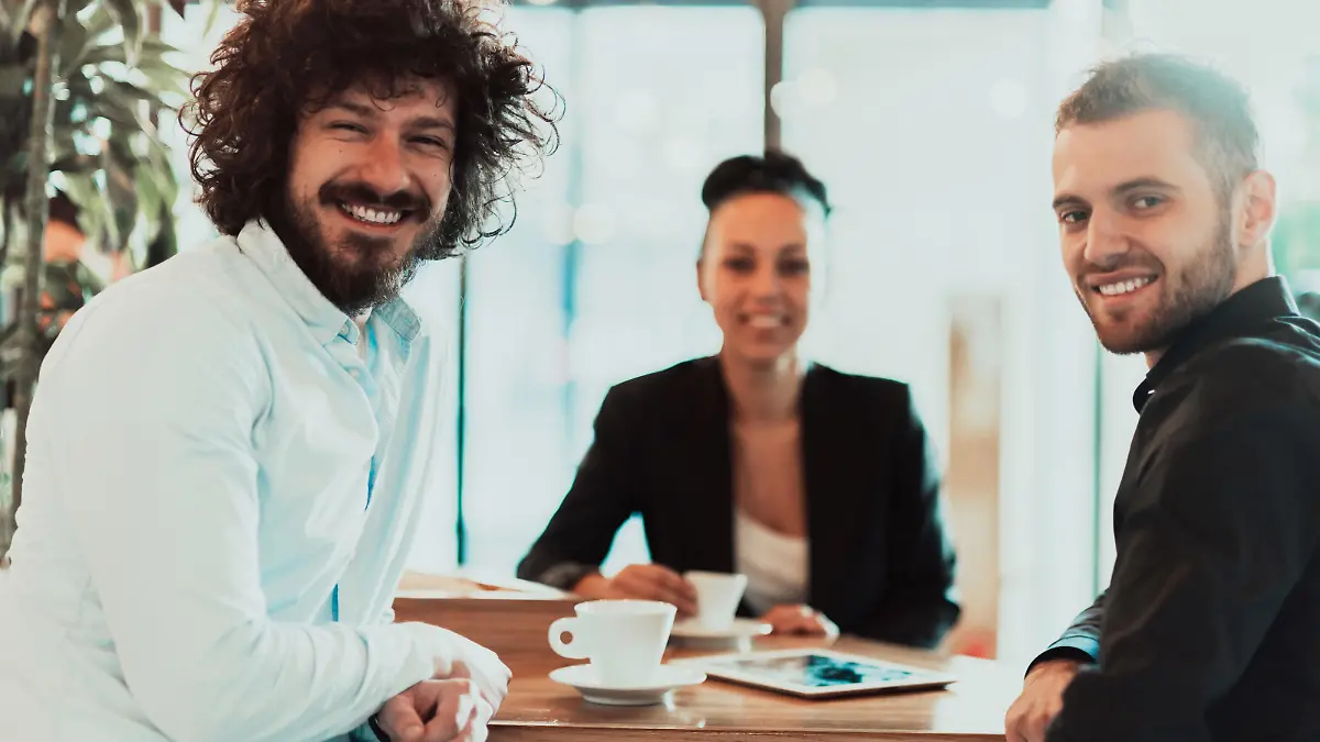 A group of businesspeople on a coffee break use laptops, tablets, and smartphones while talking about new business projects. business concept. || Modellfreigabe vorhanden