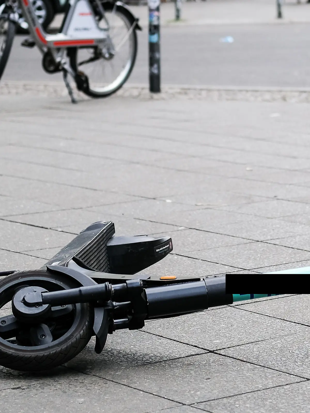 ARCHIV - 24.07.2020, Berlin: Ein E-Scooter liegt umgekippt mitten auf dem Gehweg in der Revaler Straße in Friedrichshain. Nach einem tödlichen Sturz eines Radfahrers über einen E-Roller in Gelsenkirchen ermittelt die Polizei weiter zum Hintergrund des Unfalls. (zu dpa: «Tödlicher Sturz von Radfahrer über E-Roller - Ermittlungen laufen») Foto: Jens Kalaene/dpa-Zentralbild/dpa +++ dpa-Bildfunk +++