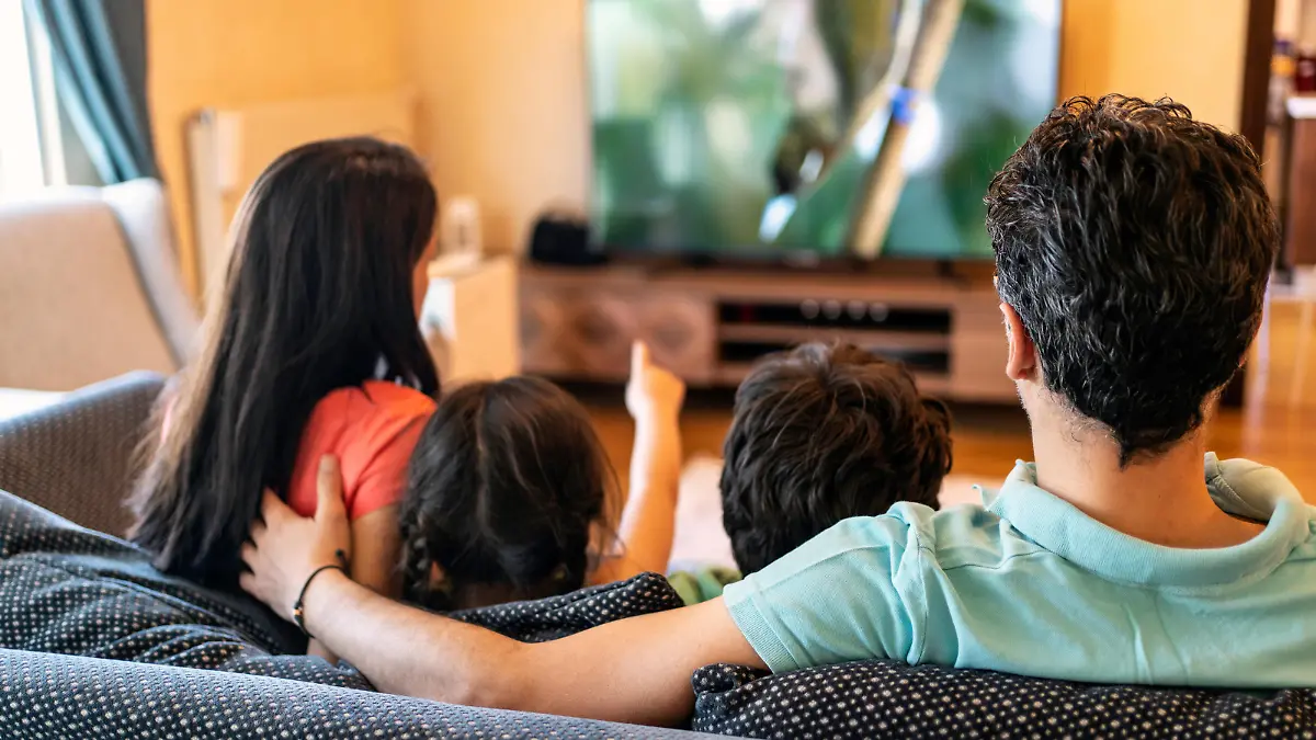 Parents and their two children watching TV together at home