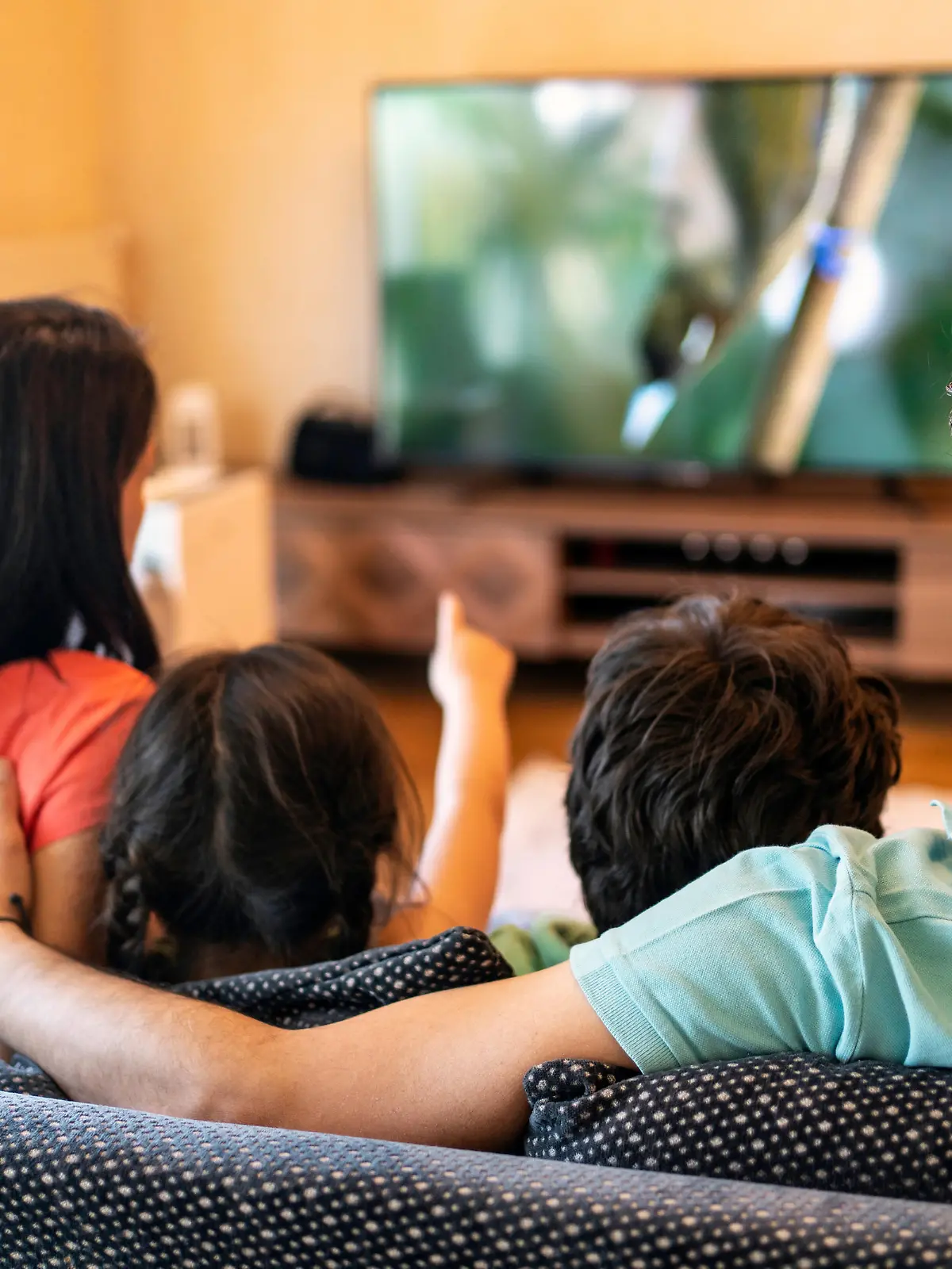 Parents and their two children watching TV together at home