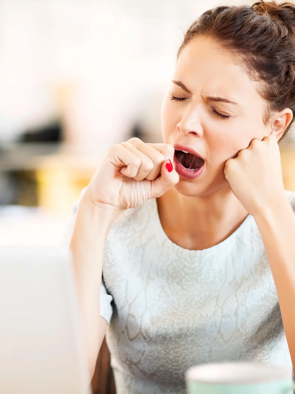 Tired female entrepreneur yawning in office. Horizontal shot.