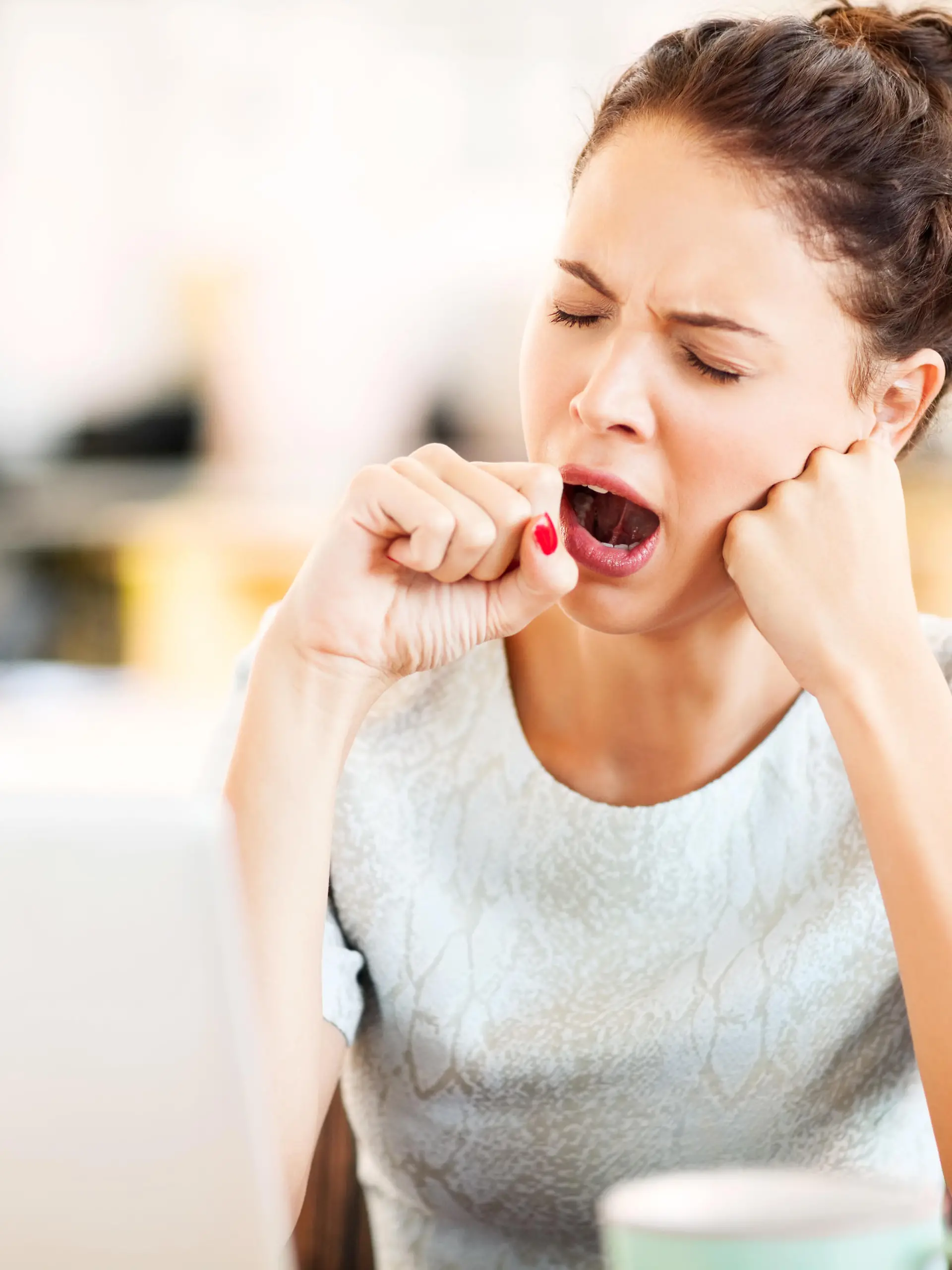 Tired female entrepreneur yawning in office. Horizontal shot.