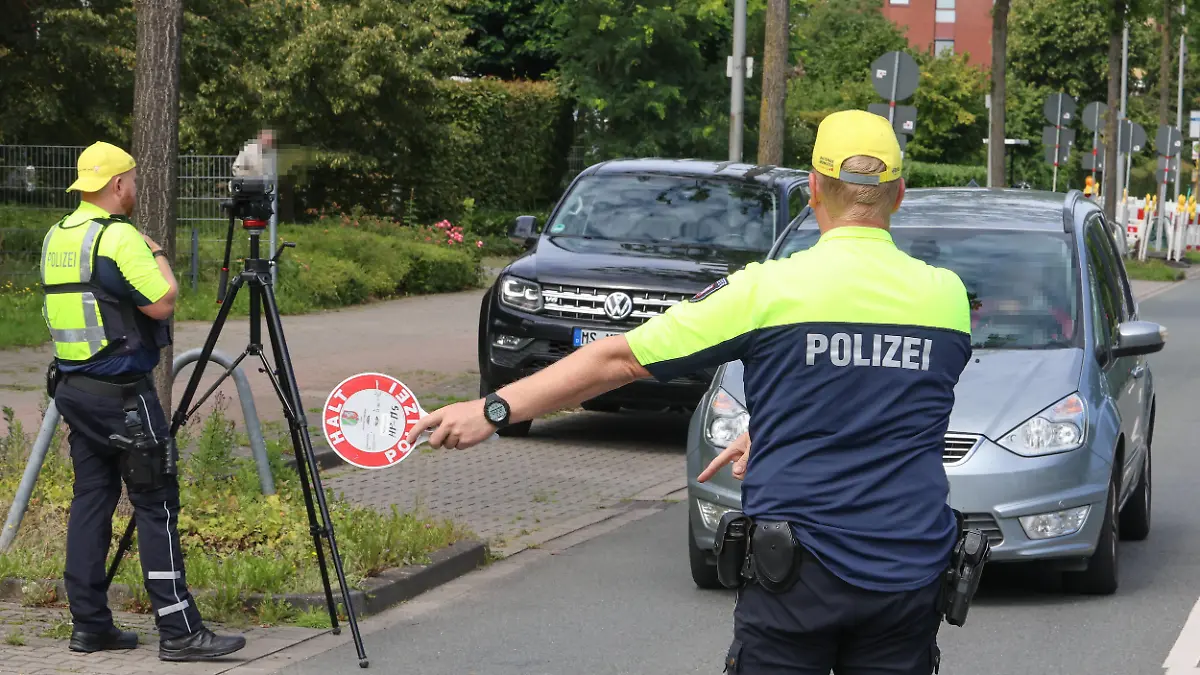 DEU, Deutschland, Nordrhein-Westfalen, Münster, 09.08.2023: Zur Einschulung startet wieder die Aktion Münster sieht gelb von Antenne Münster. Presstermin, Mediengespräch und anschließende Verkehrskontrolle des Polizeipräsidium Münster und den Kindern der Mosaik Grundschule. Verkehrssicherheitsberater der Polizei verteilen zusammen mit Schülerinnen und Schülern der Mosaik-Schule Denk- und Dankzettel an Verkehrsteilnehmer. Polizeibeamter hält ein Fahrzeug an *** DEU, Germany, North Rhine-Westphalia, Münster, 09 08 2023 For the first day of school, the campaign Münster sees yellow by Antenne Münster starts again Presstermin, media talk and subsequent traffic control of the police headquarters Münster and the children of the Mo