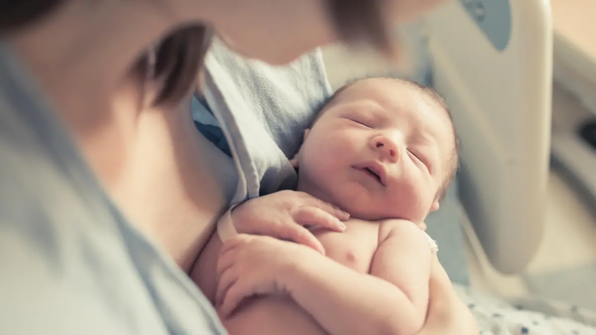 New born baby boy resting in mothers arms.