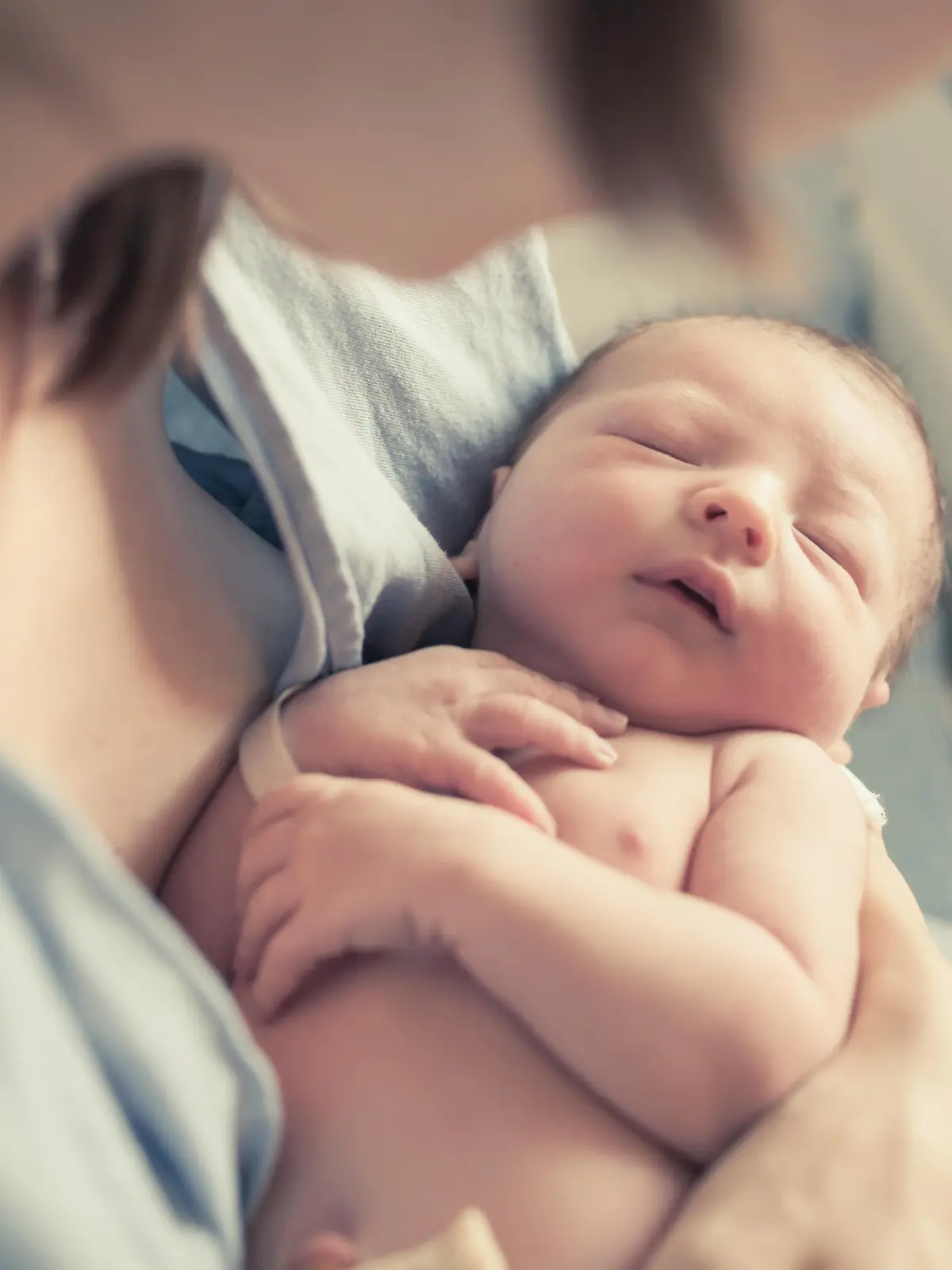 New born baby boy resting in mothers arms.
