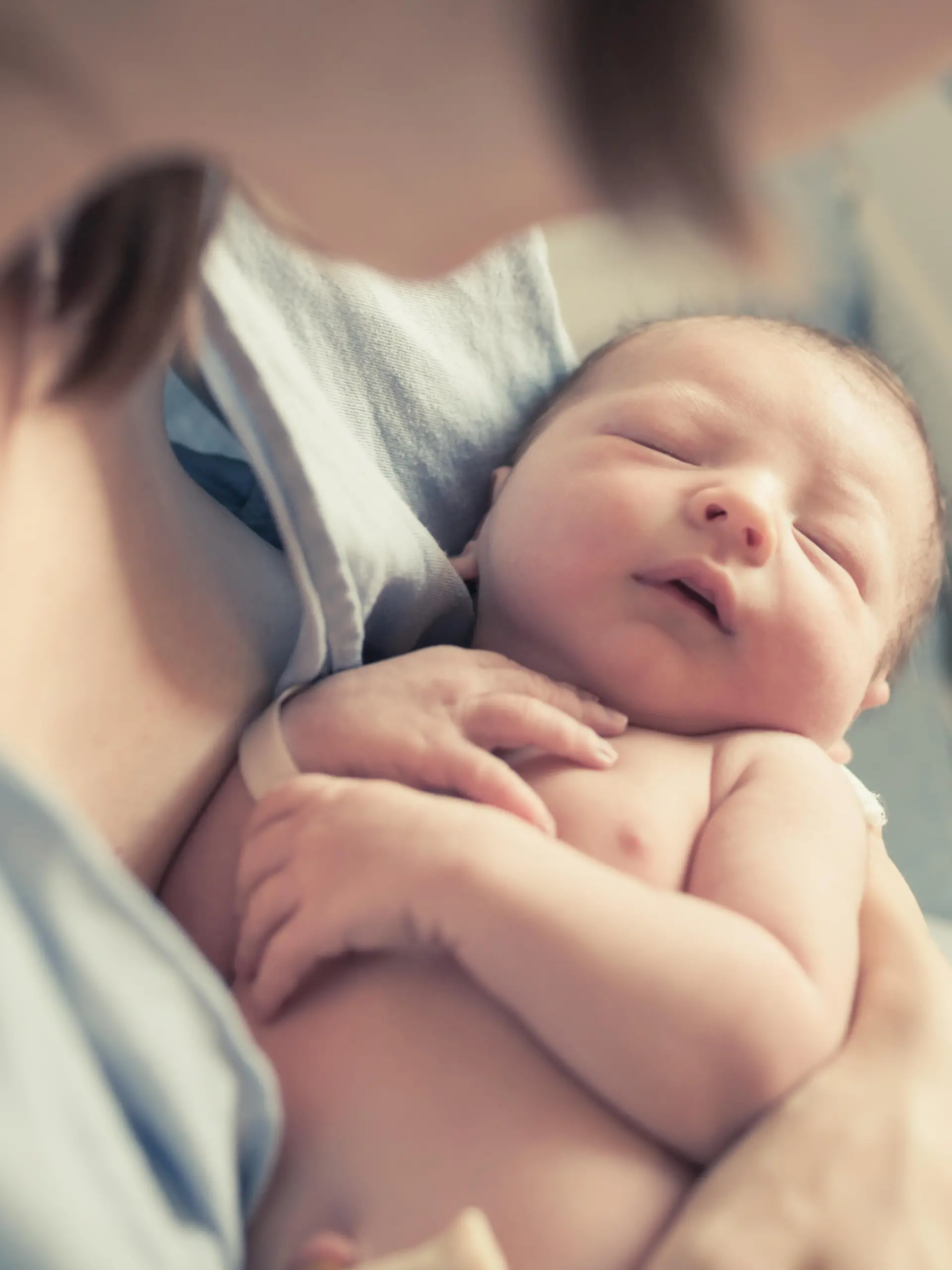 New born baby boy resting in mothers arms.