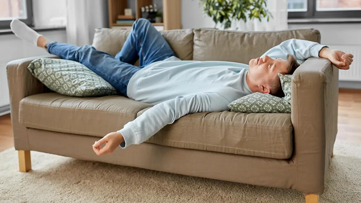 people, boredom and depression concept - bored or lazy young man lying on sofa at home || Modellfreigabe vorhanden