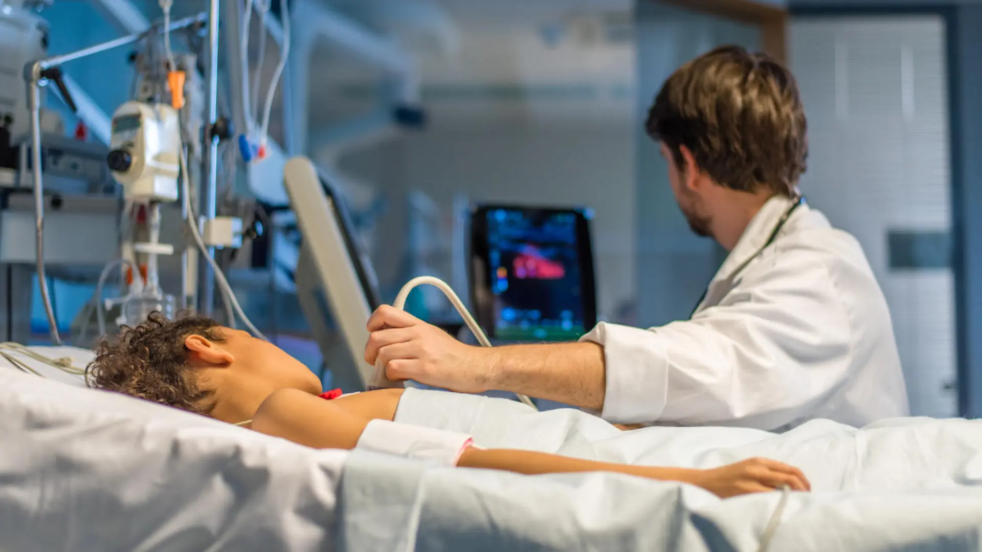 Doctor checking heart ultrasound scan of child patient in operating theatre.