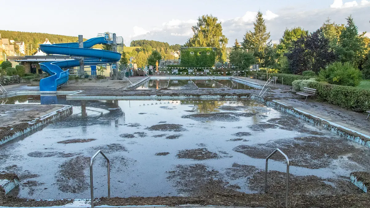 dpatopbilder - 06.09.2022, Sachsen, Burkhardtsdorf: Mit Schlamm ist ein Schwimmbecken in einem Freibad im Erzgebirge gefüllt. Nach Unwettern überrollte eine Schlammlawine das Freibad und spülte Schlamm und Geröll in die Schwimmerbecken. Die Freibad Saison ist hier für dieses Jahr beendet. Wie hoch der Schaden ist, kann mittlerweile noch nicht beziffert werden. Foto: André März/dpa +++ dpa-Bildfunk +++