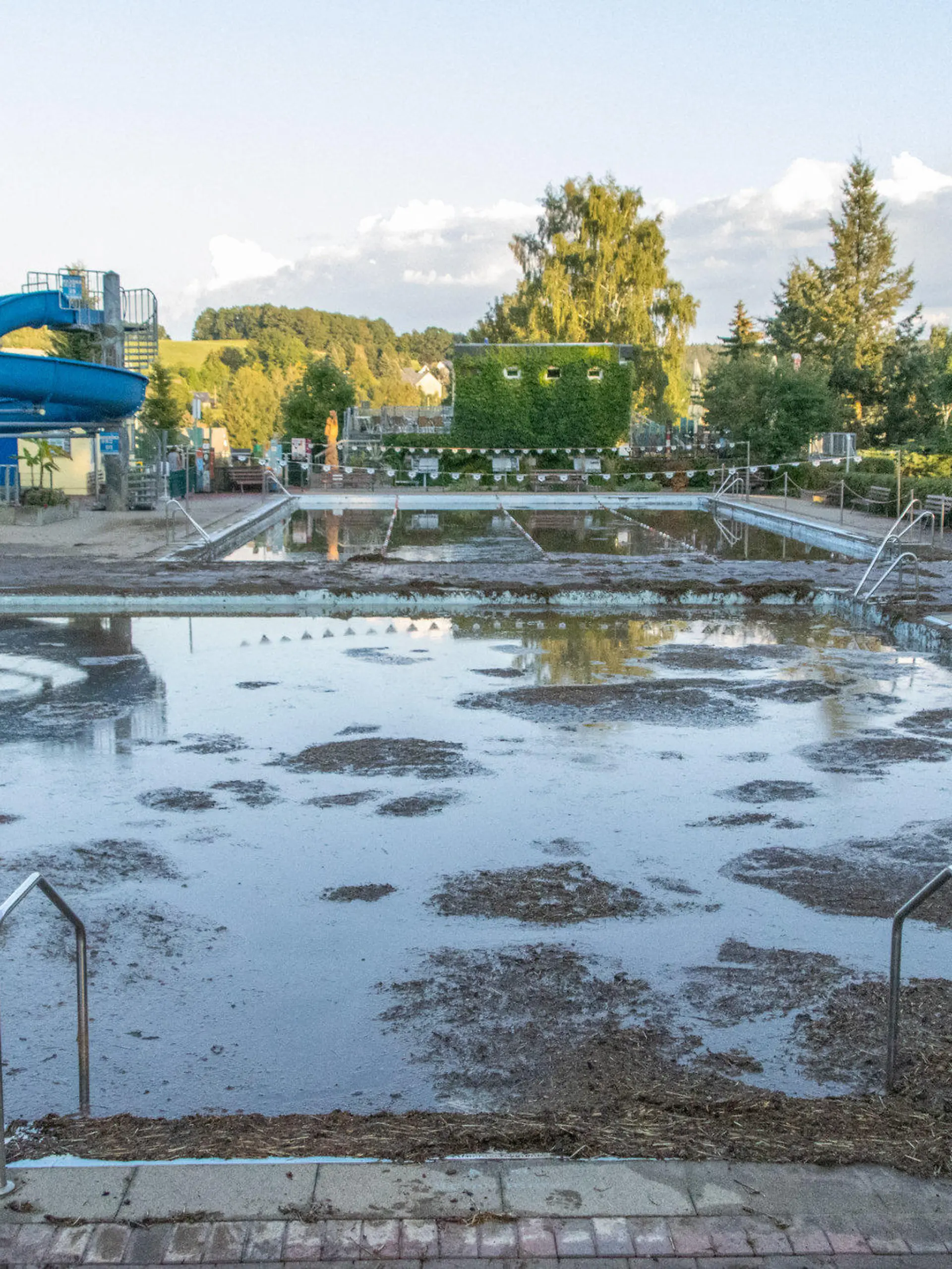 dpatopbilder - 06.09.2022, Sachsen, Burkhardtsdorf: Mit Schlamm ist ein Schwimmbecken in einem Freibad im Erzgebirge gefüllt. Nach Unwettern überrollte eine Schlammlawine das Freibad und spülte Schlamm und Geröll in die Schwimmerbecken. Die Freibad Saison ist hier für dieses Jahr beendet. Wie hoch der Schaden ist, kann mittlerweile noch nicht beziffert werden. Foto: André März/dpa +++ dpa-Bildfunk +++