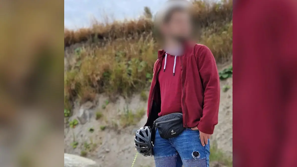 Ein Mann steht an einem Strand vor einer Düne.