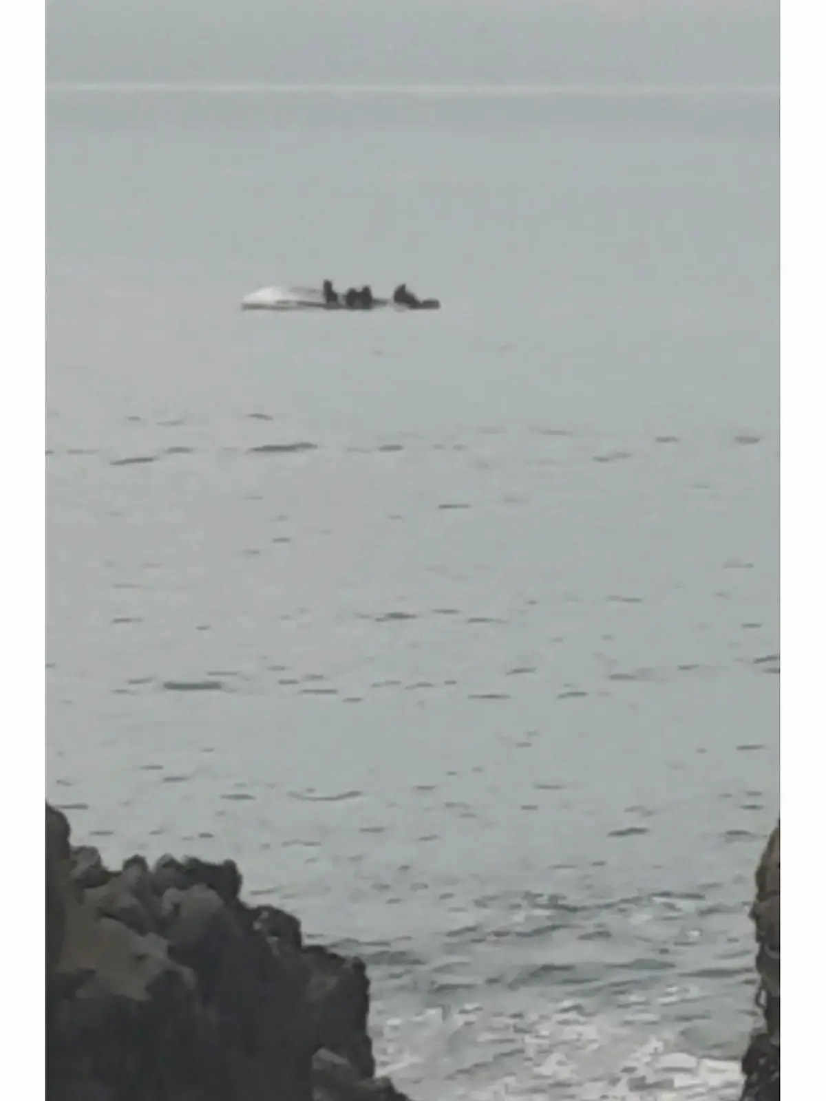 10.09.2022, Neuseeland, Kaikoura: Auf diesem Bild aus einem Video klammern sich Überlebende an den umgedrehten Rumpf eines Bootes, das am Samstag, 10. September 2022 vor der Küste von Kaikoura, Neuseeland, gekentert ist. Das Boot sei mit einem Wal zusammengestoßen und gekentert. Foto: Str/STR/dpa - ACHTUNG: Nur zur redaktionellen Verwendung im Zusammenhang mit einer Berichterstattung über dieses Bootsunglück und nur mit vollständiger Nennung des vorstehenden Credits +++ dpa-Bildfunk +++
