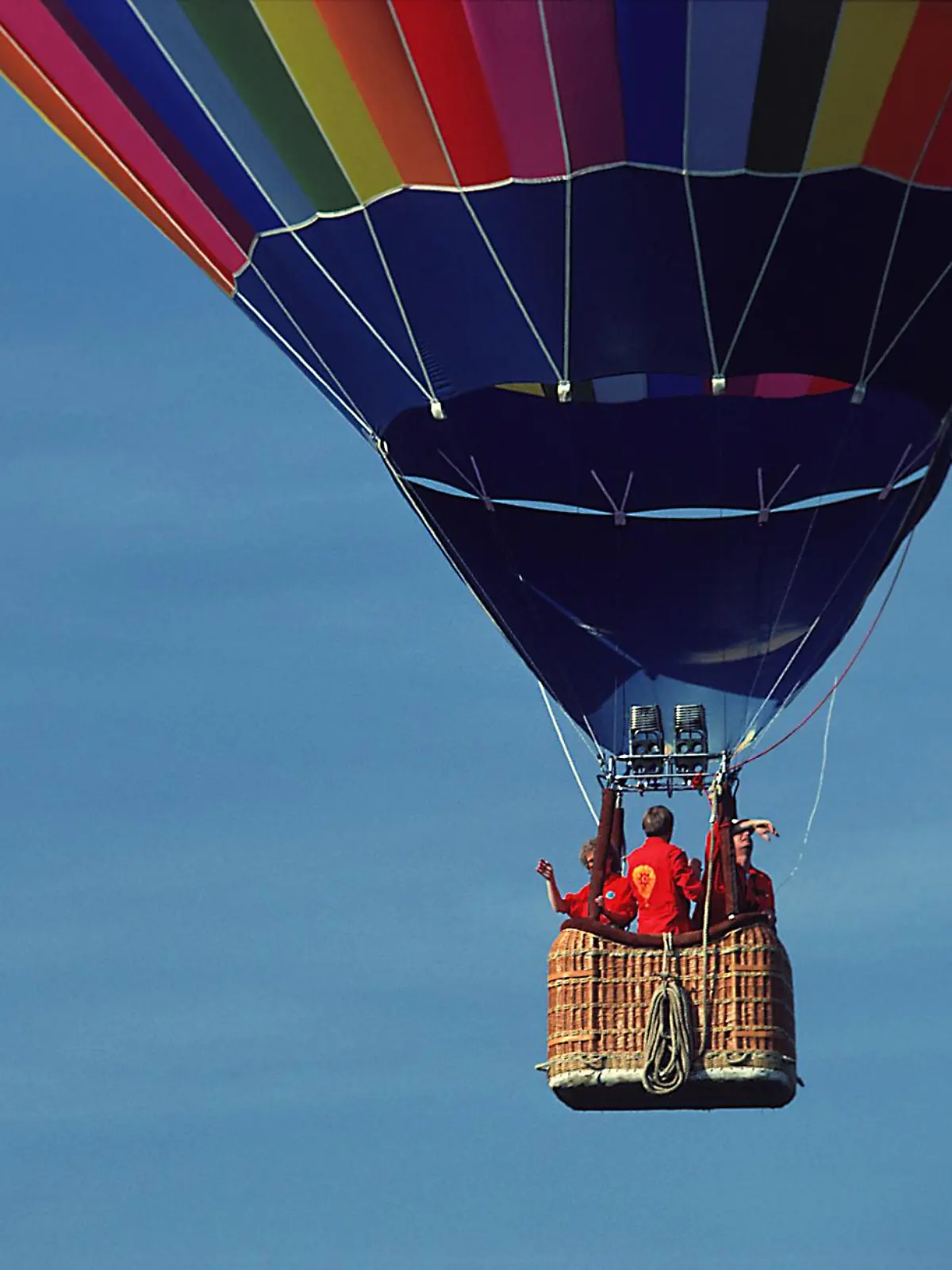 Ein Heißluftballon in der Luft mit einem blauen Himmel als Hintergrund.