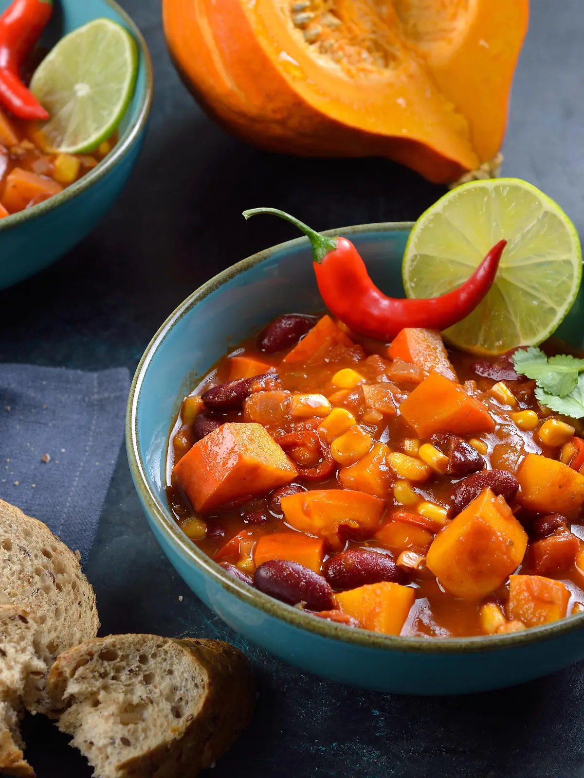 Feuriges Chili con Kürbis aus der veganen Küche mit Limette und Koriander? Hot vegan chili con calabaza from the vegan cuisine with lime and coriander served with slices of a wholemeal roll