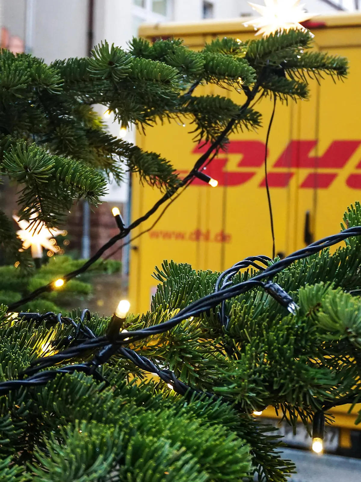 Frankenberg, Deutschland 22. Dezember 2020: Hinter einem Weihnachtsbaum ist eine Fahrzeug der DHL , Deutschen Post in einer Stadt zu sehen.