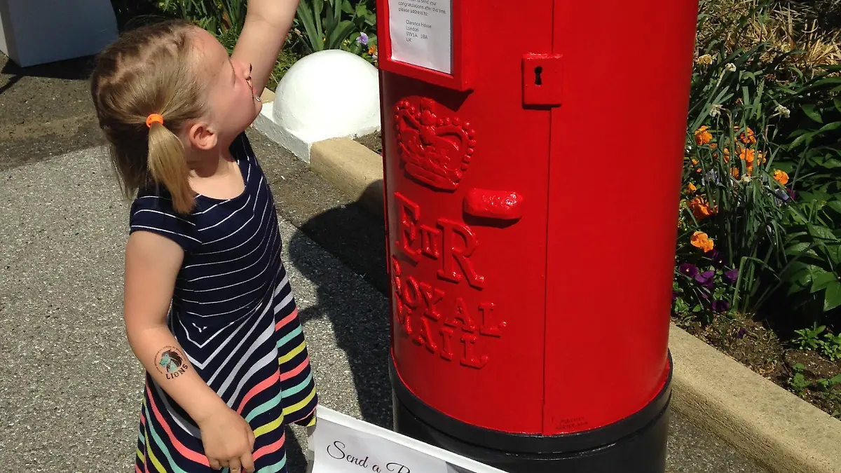 12.05.2018, USA, Washington D.C.: Die fünfjährige Millie D. wirft auf dem Gelände der britischen Botschaft ihre Hochzeitsgrüße für Harry und Meghan in einen Briefkasten. Tausende in den USA lebende Briten und Amerikaner haben die Möglichkeit genutzt, Prinz Harry und seiner Braut Meghan Markle per Grußkarte zur Hochzeit zu gratulieren. Die britische Botschaft in der US-Hauptstadt Washington hatte eigens Bilder des Paares vor einem in für Großbritannien typischen signalroten Postkasten aufgestellt. (zu dpa «Hochzeitsgrüße aus Amerika: Roter Postkasten sammelt Grußkärtchen» vom 13.05.2018) Foto: Michael Donhauser/dpa +++ dpa-Bildfunk +++