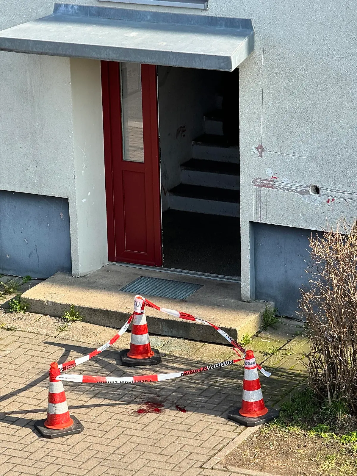 Polizisten haben in Magdeburg Blutspuren vor dem Eingang zu einem Haus mit Flatterband markiert.