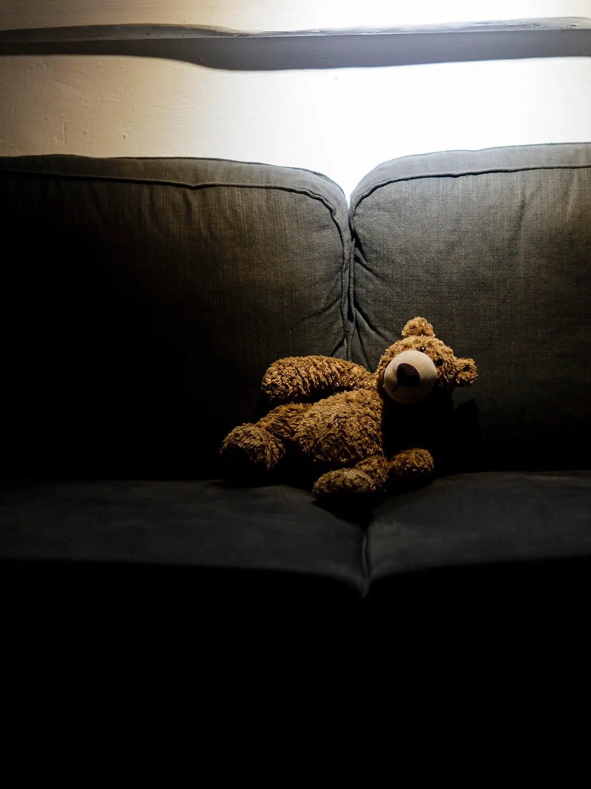 Symbolfoto zum Thema Kindesmissbrauch: Ein Teddy sitzt im Dunkeln allein auf einer Couch. Berlin, 25.03.2020.
