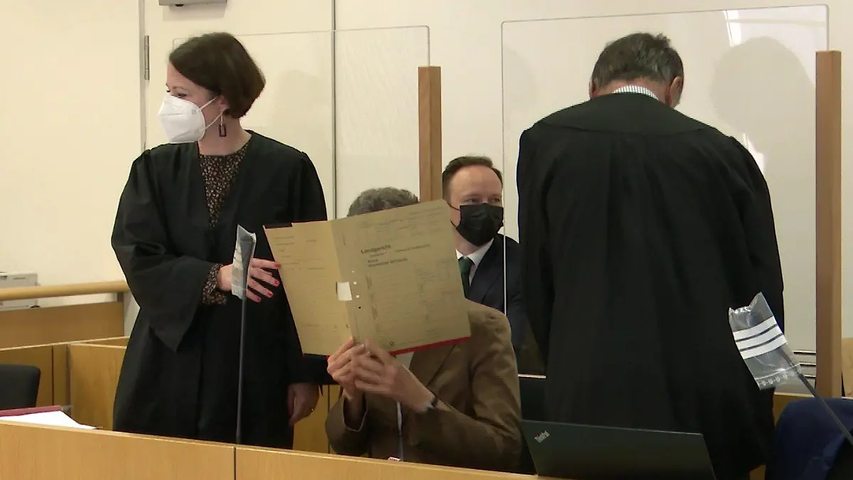 Jans Mutter Dr. Claudia H. verbirgt beim Prozessauftakt ihr Gesicht hinter einem Aktenordner.