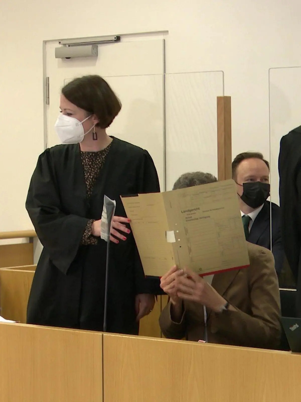 Jans Mutter Dr. Claudia H. verbirgt beim Prozessauftakt ihr Gesicht hinter einem Aktenordner.