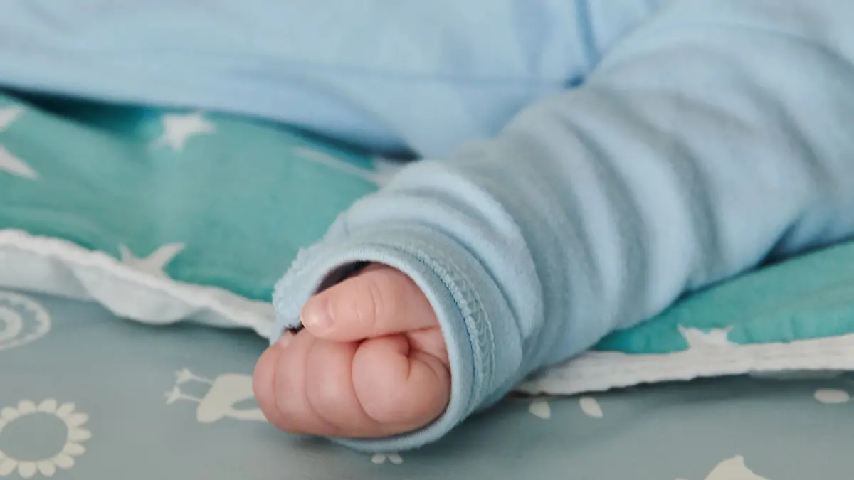 Ein wenige Wochen altes Baby ballt seine Hand zu einer kleinen Faust.