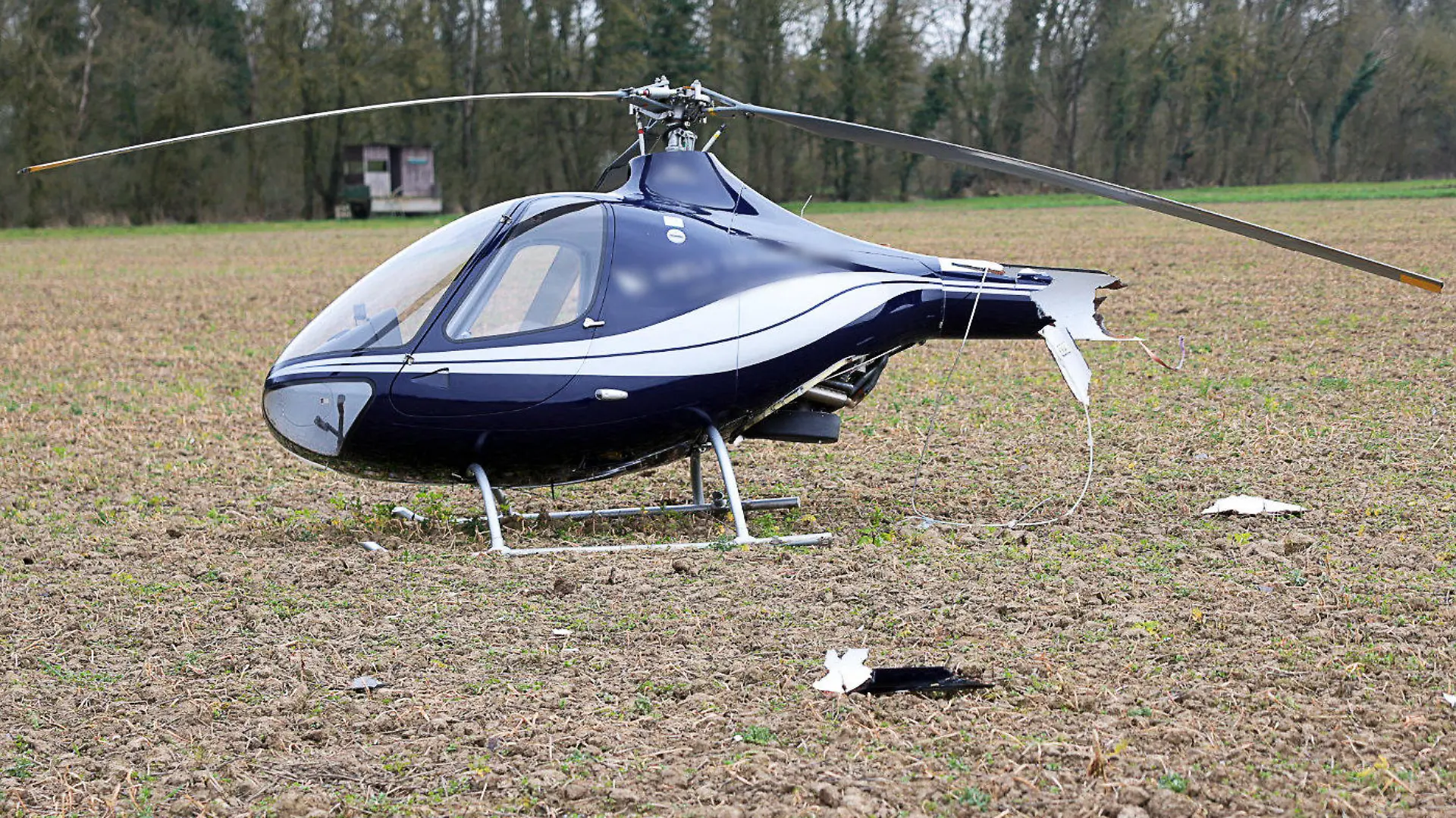 06.03.2024, Hessen, Gernsheim: Ein beschädigter Hubschrauber steht an der Absturzstelle in der Nähe einer Autobahn und einer Bundesstraße im Kreis Groß-Gerau. Nach den bisherigen Ermittlungen seien zwei Männer an Bord gewesen, beide hätten sich nicht verletzt, wie die Polizei Darmstadt mitteilte. Foto: -/5Vision.News/dpa - ACHTUNG: Kennzeichen wurde(n) aus rechtlichen Gründen gepixelt +++ dpa-Bildfunk +++