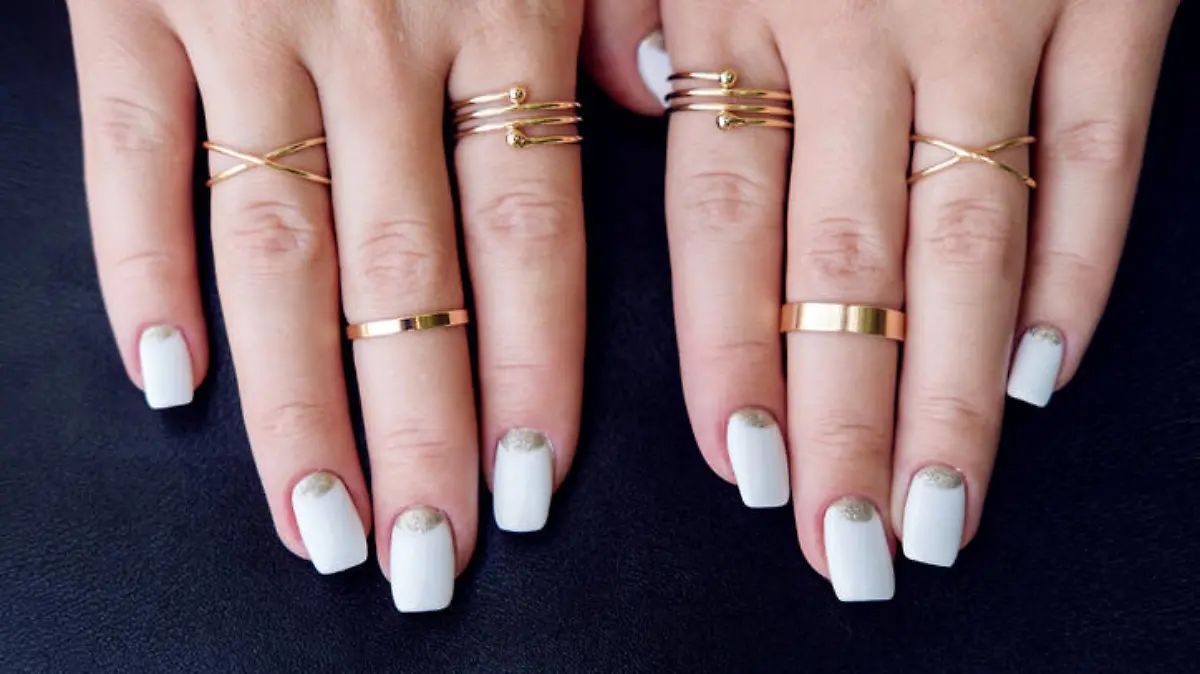 White nail art manicure, beauty hands with fashion gold rings. Trendy accessories top view