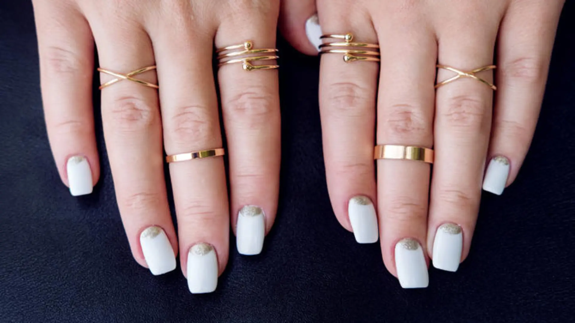 White nail art manicure, beauty hands with fashion gold rings. Trendy accessories top view