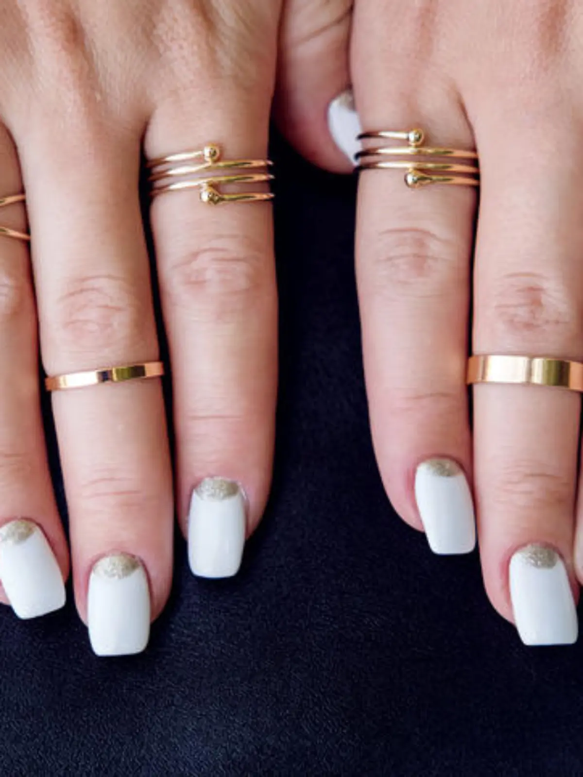 White nail art manicure, beauty hands with fashion gold rings. Trendy accessories top view