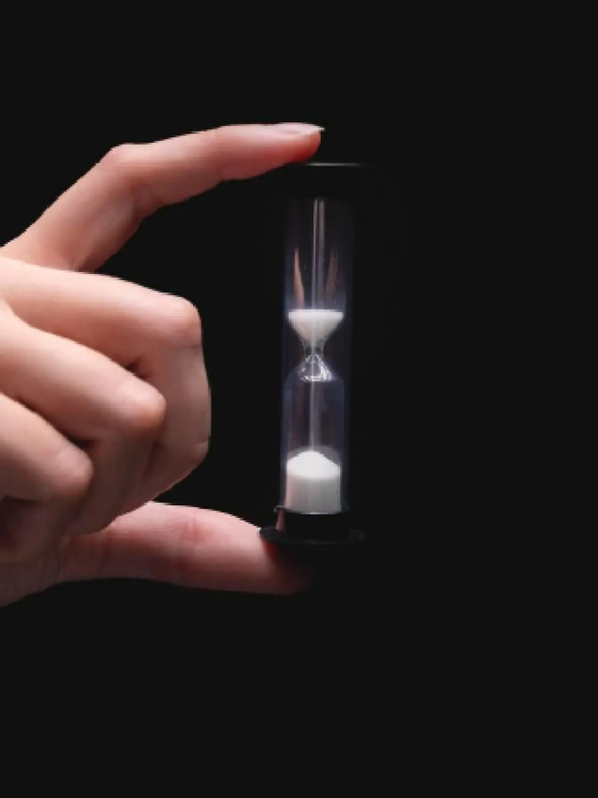 Close-up of a woman holding an hourglass. Time goes by and time runs out. Countdown timer.