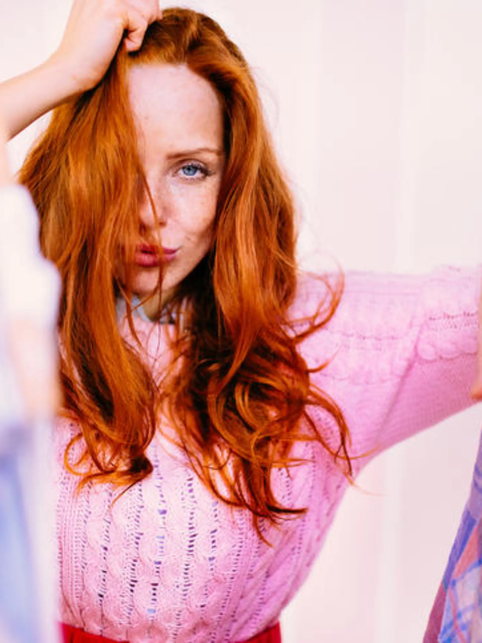Young redhead woman looking through a rail of clothing on hangers
