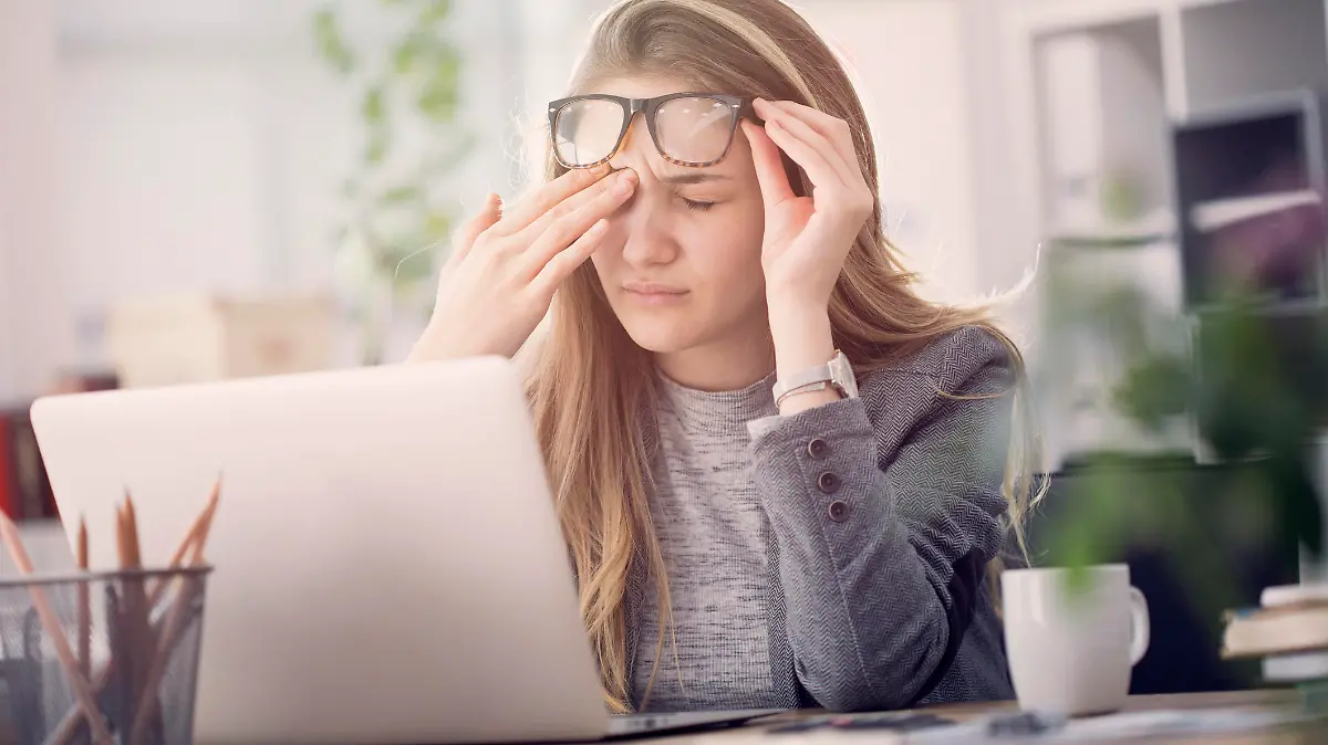 Frau sitzt müde am Laptop.