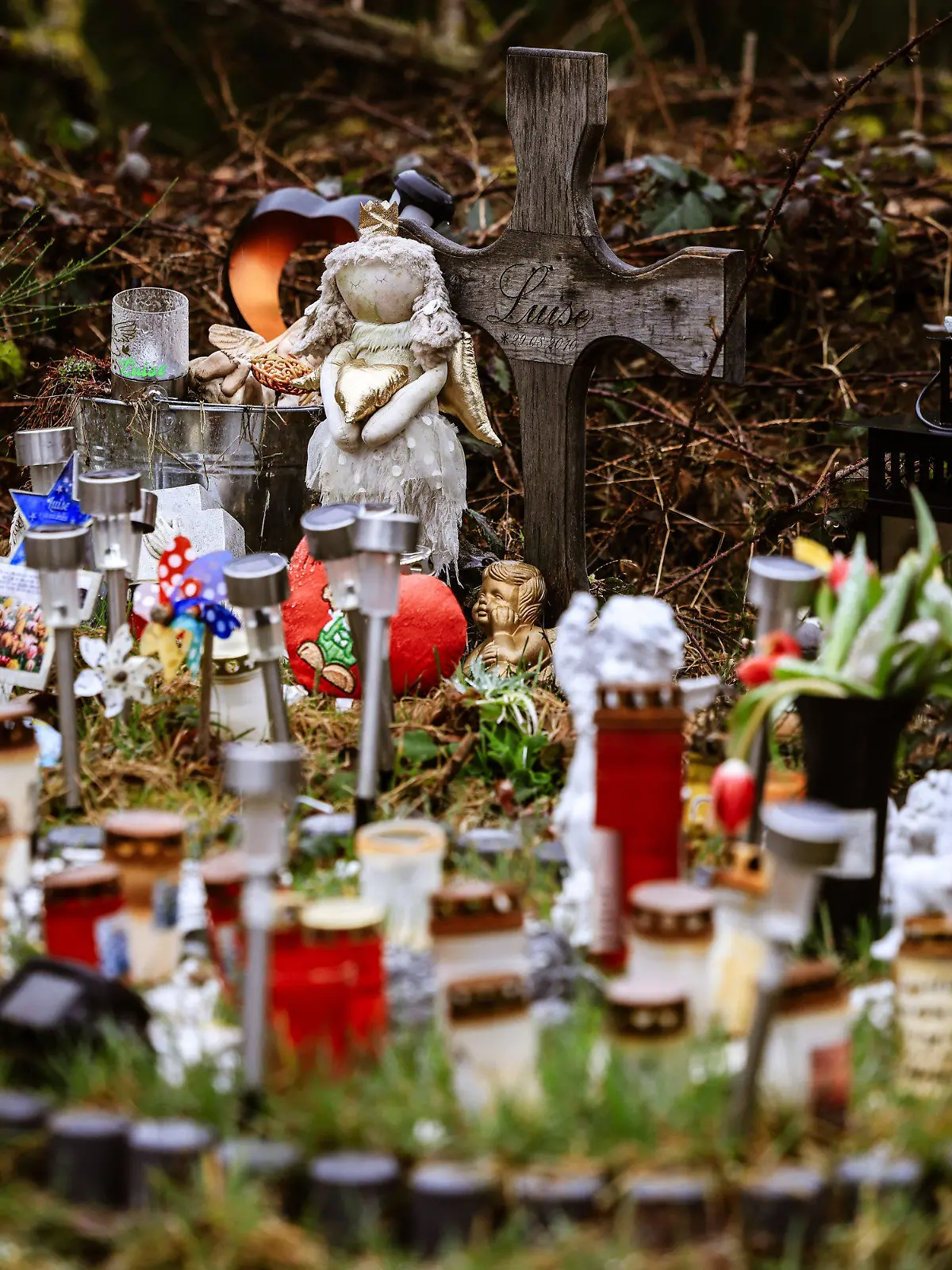 05.03.2024, Nordrhein-Westfalen, Freudenberg: Kerzen, Blumen und Figuren liegen am Fundort an der Landesgrenze zwischen Rheinland-Pfalz und Nordrhein-Westfalen. Die zwölf Jahre alte Schülerin Luise war im März 2023 erstochen worden. Zwei strafunmündige Mädchen hatten die Tat gestanden. (Zu dpa: «Ein Jahr nach gewaltsamen Tod von Luise - das Entsetzten bleibt») Foto: Oliver Berg/dpa +++ dpa-Bildfunk +++