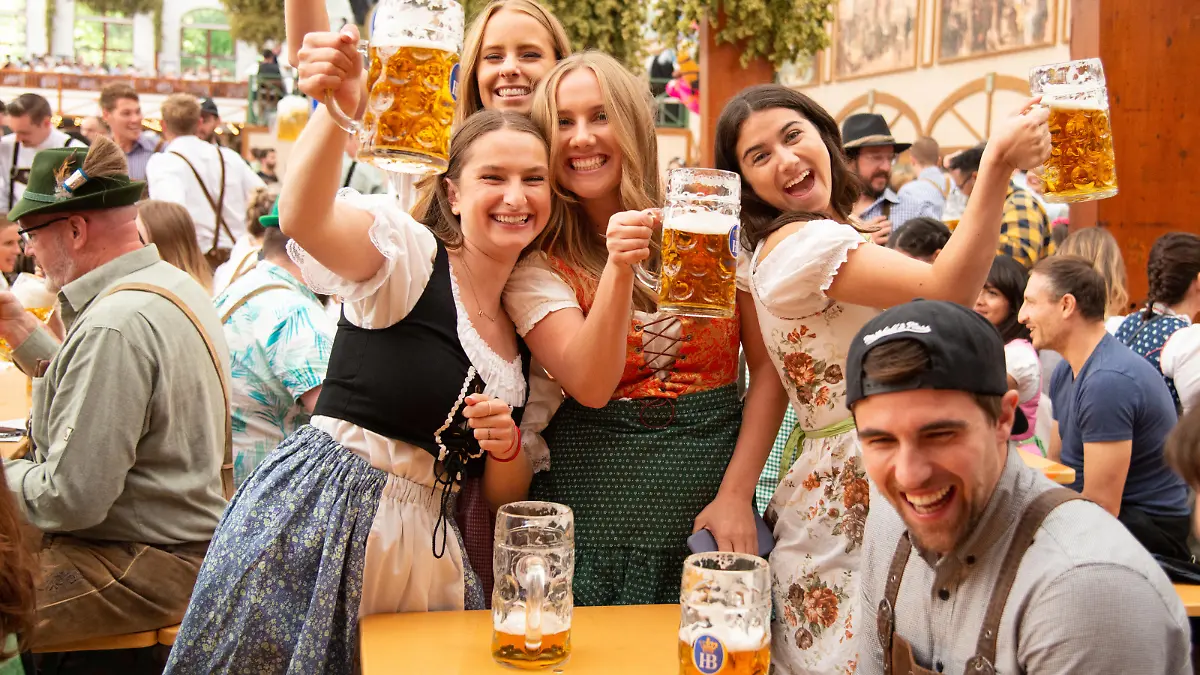 Munich, Germany - September 21, 2019: Oktoberfest in Munich, Germany. A group of young people in beer hall, celebrating Oktoberfest on Theresienwiese. People are dressed in traditional clothes and holding beer glass. The Oktoberfest is the largest fair in the world and is held annually in Munich.