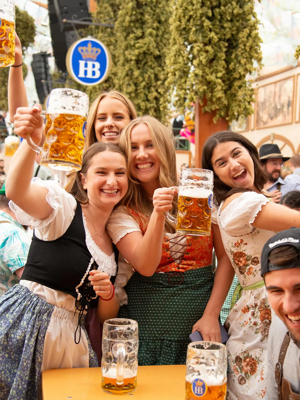 Munich, Germany - September 21, 2019: Oktoberfest in Munich, Germany. A group of young people in beer hall, celebrating Oktoberfest on Theresienwiese. People are dressed in traditional clothes and holding beer glass. The Oktoberfest is the largest fair in the world and is held annually in Munich.